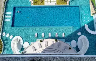 The Residences @ Dream Pattaya outdoor swimming pool with blue tiles, lounge chairs, and a white spiral staircase.