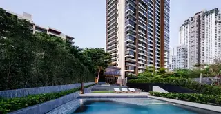 Baan Plai Haad tall condo building exterior with a modern swimming pool and lush landscaping.