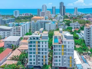 Estanan Condo: Aerial view of two identical condo buildings with rooftop pools, set against a cityscape and the ocean.