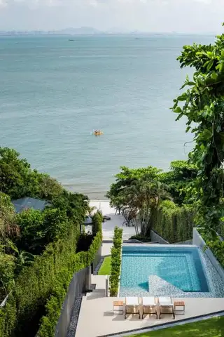 Baan Plai Haad infinity pool overlooking the ocean, with a private beach and lush green foliage.