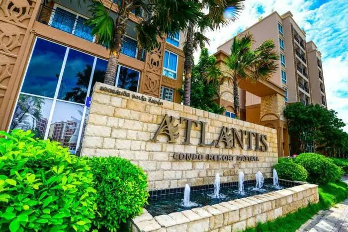Atlantis Condo Resort entrance sign made of stone with fountains and palm trees, leading to the building facade.