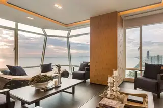 Reflection Jomtien Beach: Outdoor balcony with dining table set for two, overlooking the ocean at sunset.