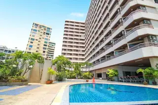 Kieng Talay outdoor swimming pool with surrounding greenery and tall residential buildings under a blue sky.