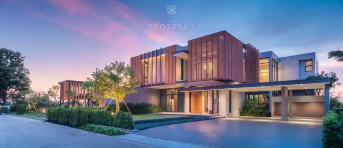 The Prospect modern luxury condo building exterior at dusk, with a large driveway, landscaping, and illuminated interiors.