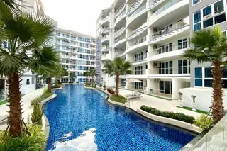 Grand Avenue Residence expansive swimming pool with a water slide, rock feature, and palm trees between condo towers.