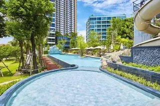 Unixx South Pattaya large multi-level swimming pool complex with water slides, sun loungers, and surrounding buildings.