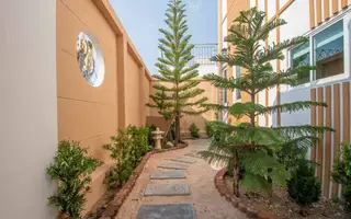 Narita Villa narrow side garden pathway with stepping stones, small trees, and decorative wall features.