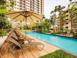 Unixx South Pattaya long outdoor swimming pool with lounge chairs, umbrellas, and surrounding tropical landscaping.