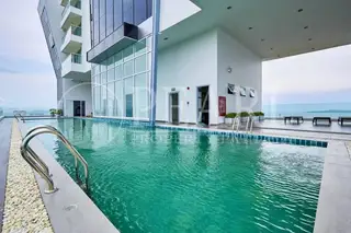 The Vision: Rooftop swimming pool with blue tiles, surrounded by a building facade and distant ocean views.