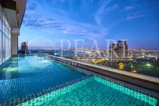 The Vision: Rooftop infinity pool at dusk, reflecting city lights and the illuminated Pattaya skyline.