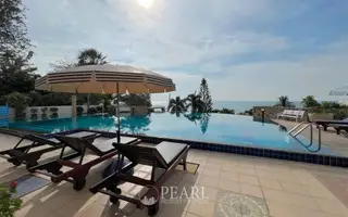Baan Rimpha swimming pool area with blue and white striped umbrella, wooden sun loungers, and lush greenery.