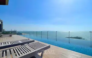 Avatara Condominium rooftop infinity pool overlooking the ocean and city skyline with lounge chairs.