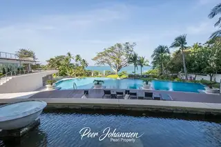 The Cove Pattaya large outdoor swimming pool area with wooden deck, sun loungers, and ocean view.