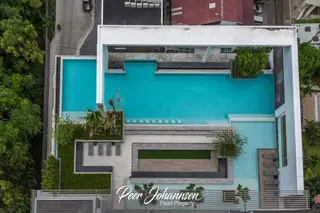 Aeras aerial view of the multi-level swimming pool area with lounge beds and greenery.
