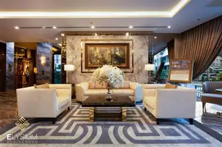 Elysium Residences elegant lounge area with cream sofas, marble wall, and geometric rug.