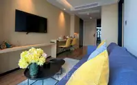 1 Bedroom Condo for Sale at Beverly Mountain Bay Pattaya modern living room with blue sofa, wall-mounted TV, and yellow dining chairs