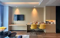 1 Bedroom Condo for Sale at Beverly Mountain Bay Pattaya living area with wall-mounted TV, built-in shelving, and yellow dining chairs