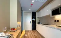 1 Bedroom Condo for Sale at Beverly Mountain Bay Pattaya compact kitchen with white marble countertops, white cabinets, and front door