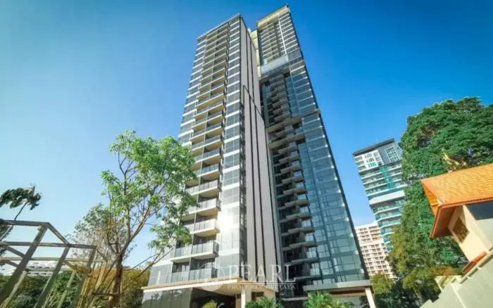 Andromeda Condominium tall modern building with glass facade and balconies against a clear blue sky.