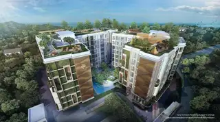 ECO Resort aerial view of modern condo buildings with green facades, rooftop gardens, and a central pool, surrounded by lush trees near the ocean.