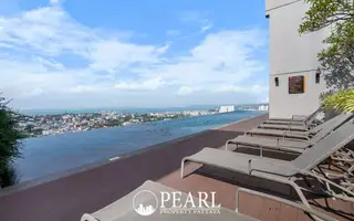 Pattaya Posh rooftop terrace with sun loungers, an infinity pool, and city views.