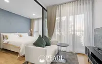 1 Bedroom Condo for Sale at Aquarous Jomtien Pattaya: Bedroom with large bed, small sofa, and floor-to-ceiling windows.