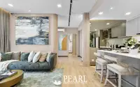 3 Bedroom Condo for Sale at Aquarous Jomtien Pattaya: Elegant living area with sofa, abstract art, and kitchen island with bar stools.
