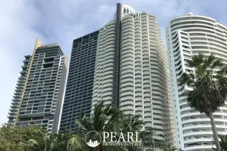 Zire Wongamat three tall condo towers against a blue sky with palm trees in the foreground.