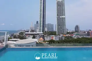 Neo Sea View rooftop pool with city skyline, tall buildings, and ocean in the distance under a blue sky.