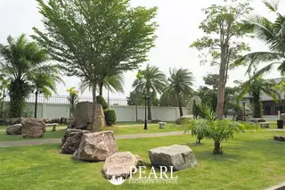 Baan Piam Mongkhon wide paved road leading into the residential community with green verges.