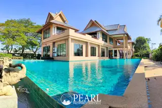Nibbana Shade large house with traditional Thai roof beside an expansive swimming pool with an elephant statue.