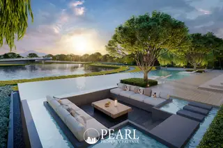 Wisdom First Residences outdoor lounge area with sofas in a shallow pool, overlooking a lake at sunset.