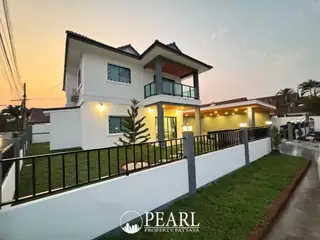 Park Rung Ruang modern two-story house exterior with balcony, fenced yard, and carport at dusk.