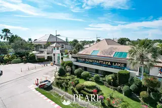 Baan Dusit Pattaya Lake 2 outdoor swimming pool with blue tiles, stone elephant statues, and a modern house.