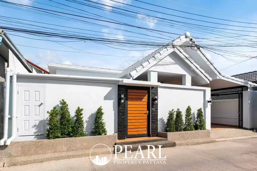 Suksabai Villa white single-story house exterior with green ornate fence, gate, and covered carport.