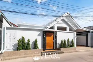 Suksabai Villa white single-story house exterior with green ornate fence, gate, and covered carport.