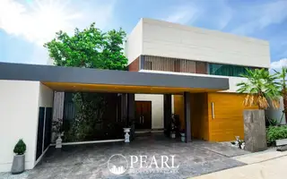 Manruetra Pura Pattaya aerial view of modern houses with green roofs and lush landscaping, overlooking the sea.