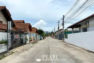 Eakmongkol Village Chaiyapruek modern house exterior with a covered patio, outdoor seating, and dark gray columns.