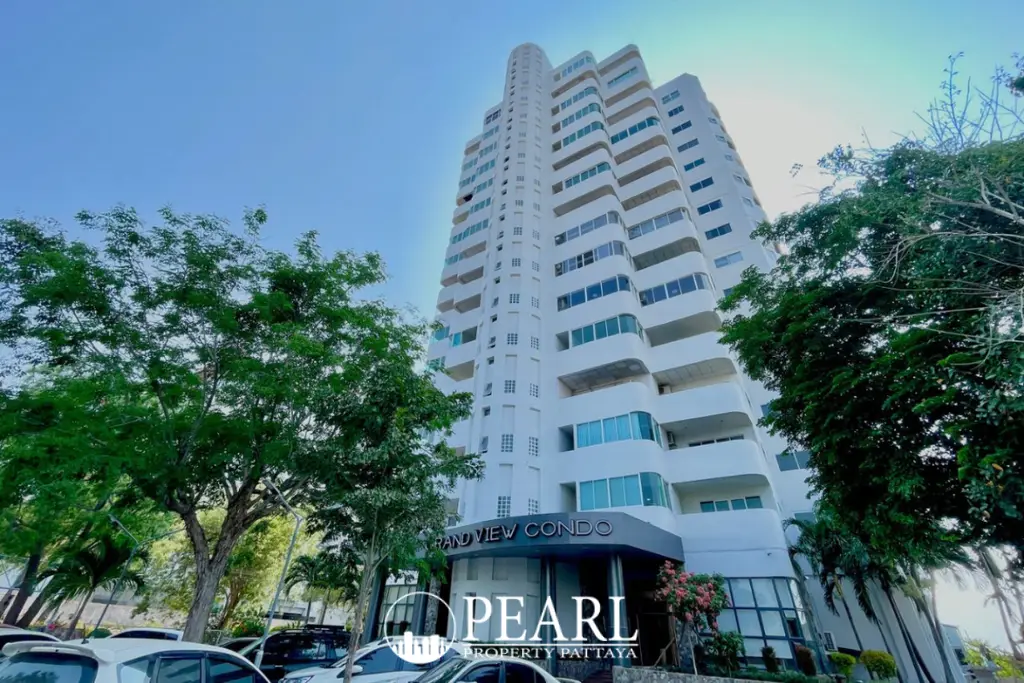 Grand View Condo exterior, a tall white building with curved balconies and blue windows, seen from a low angle surrounded by green trees.