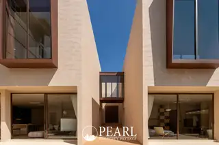 Villa Barrera: Modern facade with a narrow central entrance, large windows, and a clear blue sky above.