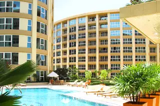 City Garden Pattaya swimming pool with lounge chairs, umbrellas, and apartment buildings in the background.