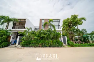 Maxx Pattaya modern white villas with large windows, surrounded by lush green tropical landscaping and palm trees.