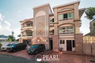 Little Norway Condominium exterior view of the building with parked cars and a Pattaya city tower in the background.