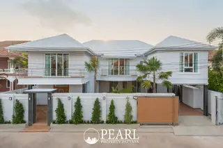 Pattaya Lagoon Village modern white house exterior with gated entrance and driveway under a clear sky.