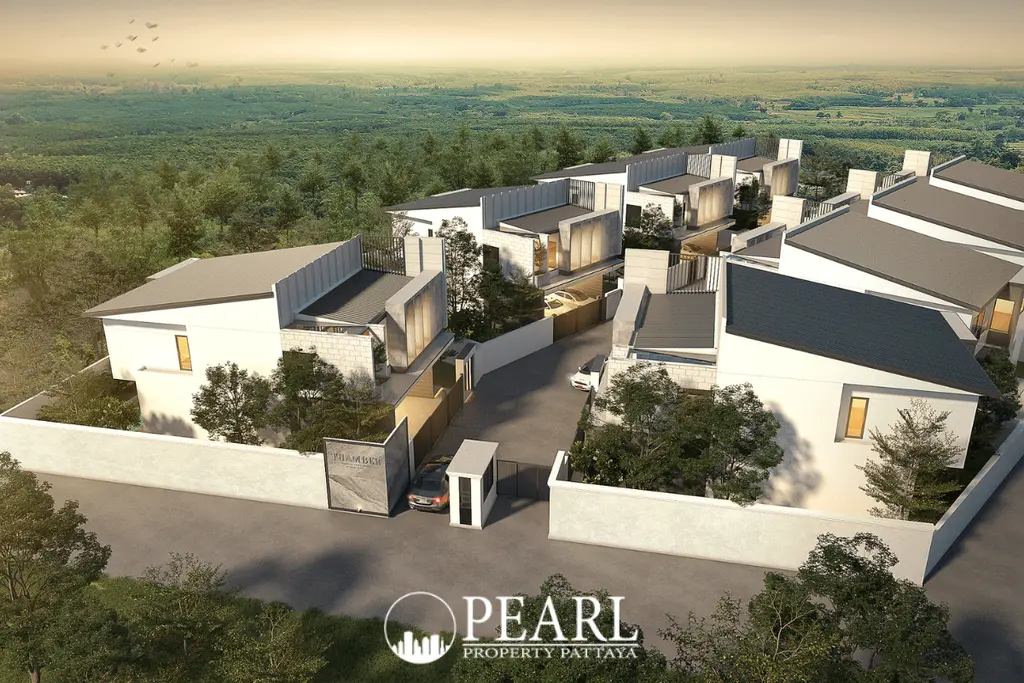 Thamber Private Pool Villa aerial view of modern villas nestled in a green forest, with a gated entrance and road.