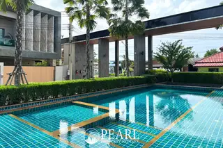 Madcha Nirvana communal swimming pool with blue tiles, surrounded by green hedges and modern architecture.
