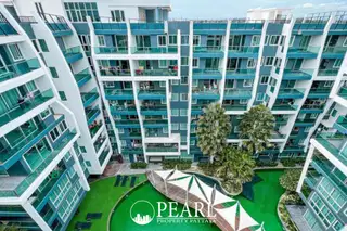 The Feelture Condominium aerial view of the building exterior, lush green lawn, and unique pool area with shade structures.
