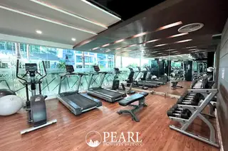 The Feelture Condominium indoor gym with treadmills, exercise bikes, weights, and large windows overlooking the property.