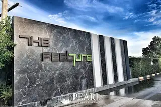 The Feelture Condominium entrance sign with a dark marble-like facade and green lettering under a blue sky.