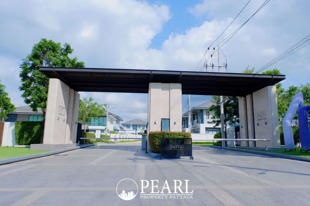Patta Ville main entrance gate with security booth and modern houses in the background under a blue sky.